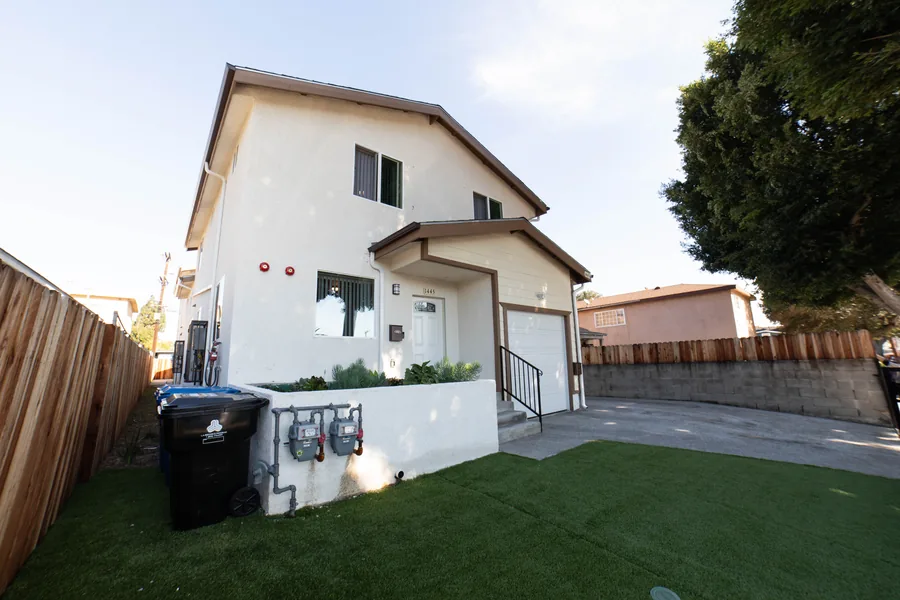 Side view of the two story East 54th Street house in Los Angeles showing the upper unit and the side yard