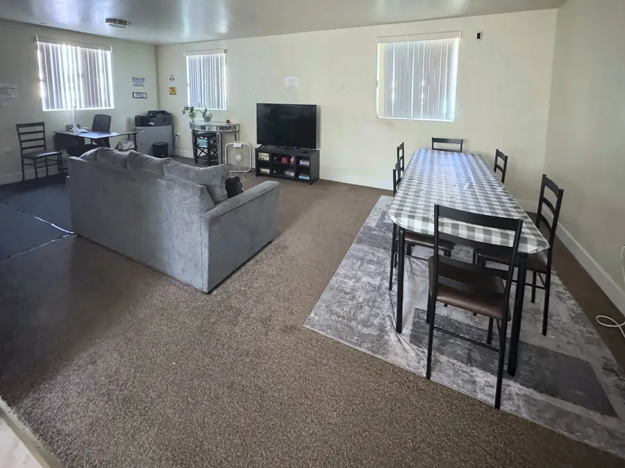 Common room and dining table at the East 69th Street house with a sofa a television and a dining table