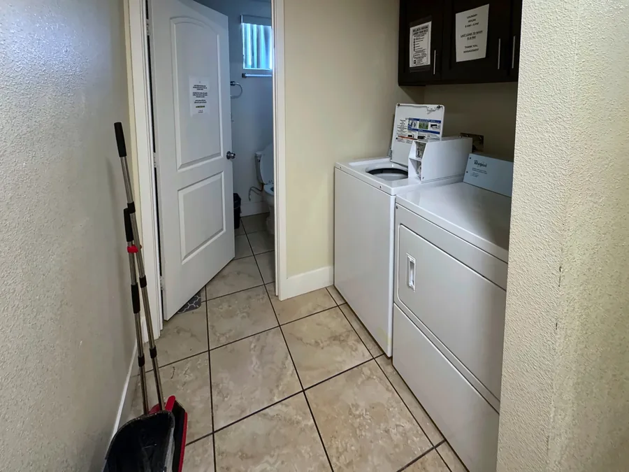 Laundry area with a washer and dryer beside a bathroom door at the East 69th Street house